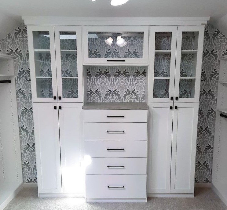 white wardrobe with drawers and cabinets with glass doors and blue and grey wallpaper
