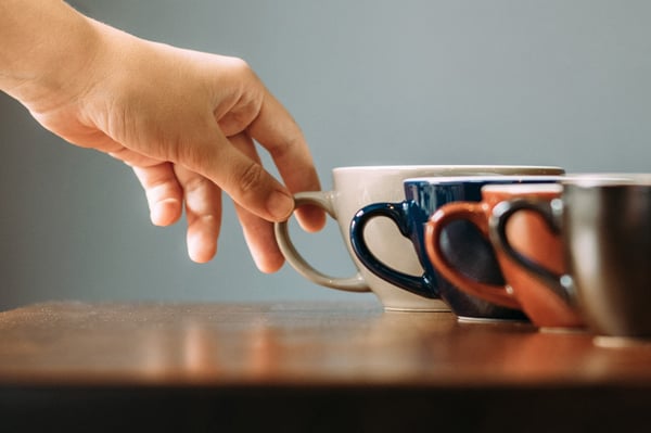 Man reaches for coffee, a trigger for tinnitus in some.