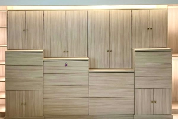 Modern custom built-in with light wood cabinetry, concealed storage, layered drawers, and integrated lighting.