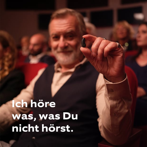 Mann im Konzert hält das neue Phonak Infinio Hörgerät zwischen den Fingern