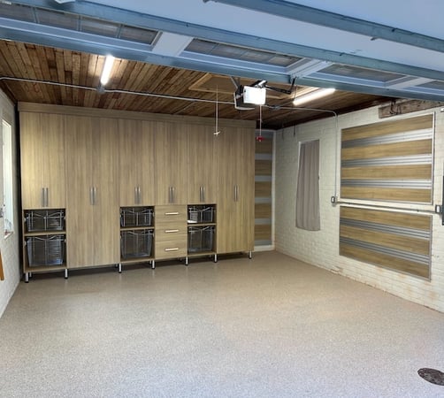 Custom garage storage with woodgrain cabinets, pull-out baskets, and fusion track wall