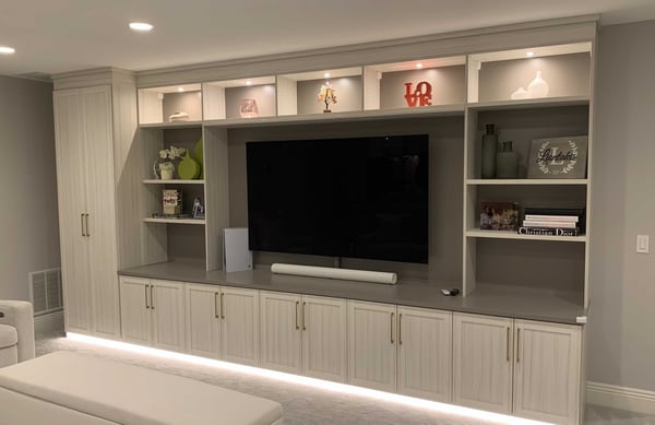media center with shelves, cabinets and TV in center with bench in white wood tone