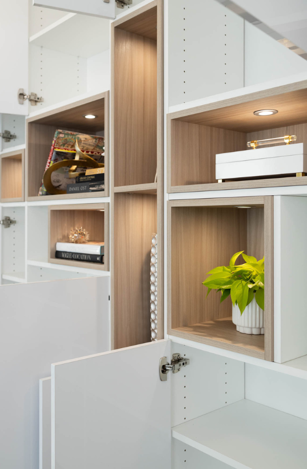 modern white high gloss shiny wall unit in drs office waiting room with different sizing natural wood cubbies in the middle for display collectibles with puck lighting Rye New York