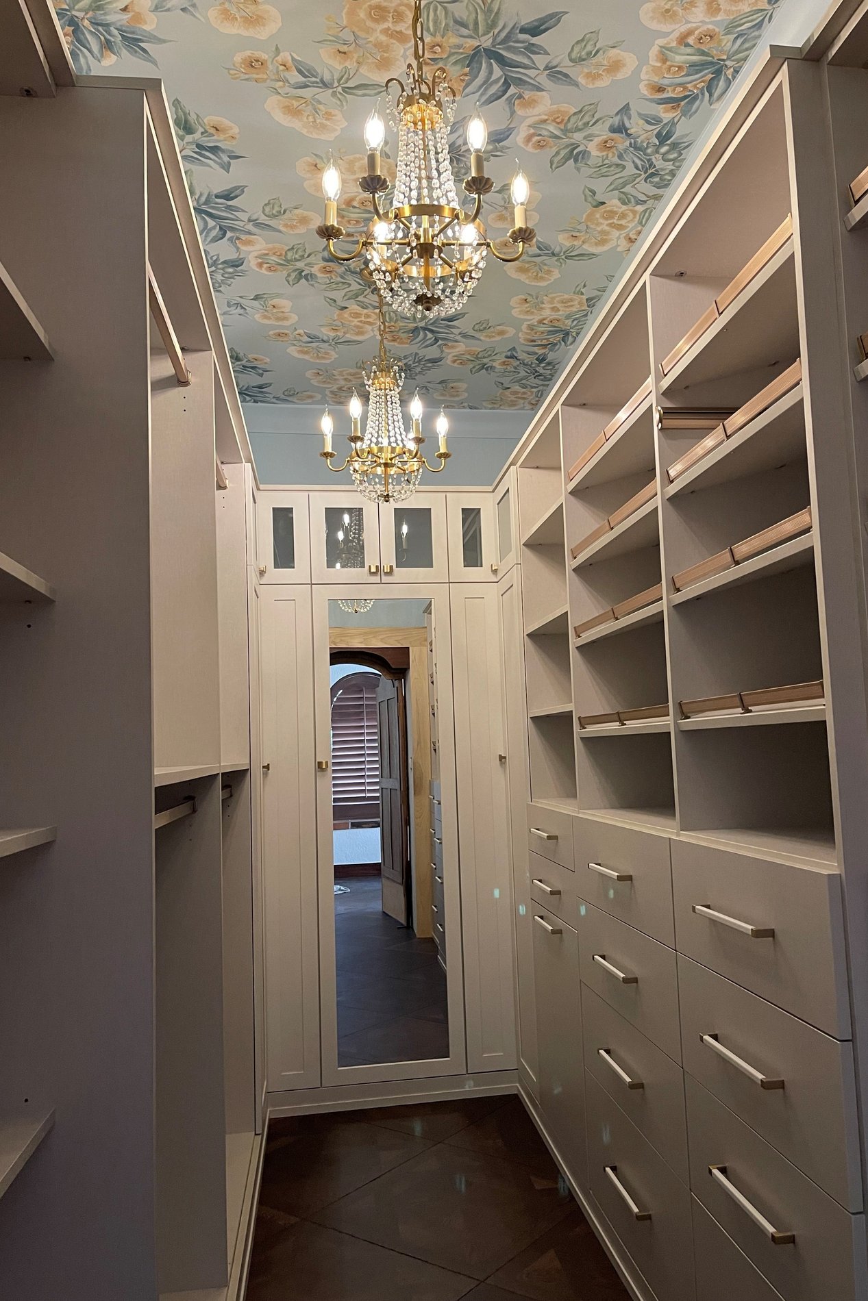 Linen-finish Narnia closet with gold hardware, winter leather wrapped handles, and shaker doors with clear glass and mirror inserts.
