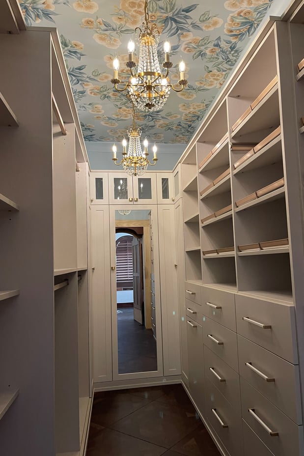 Linen-finish Narnia closet with gold hardware, winter leather wrapped handles, and shaker doors with clear glass and mirror inserts.