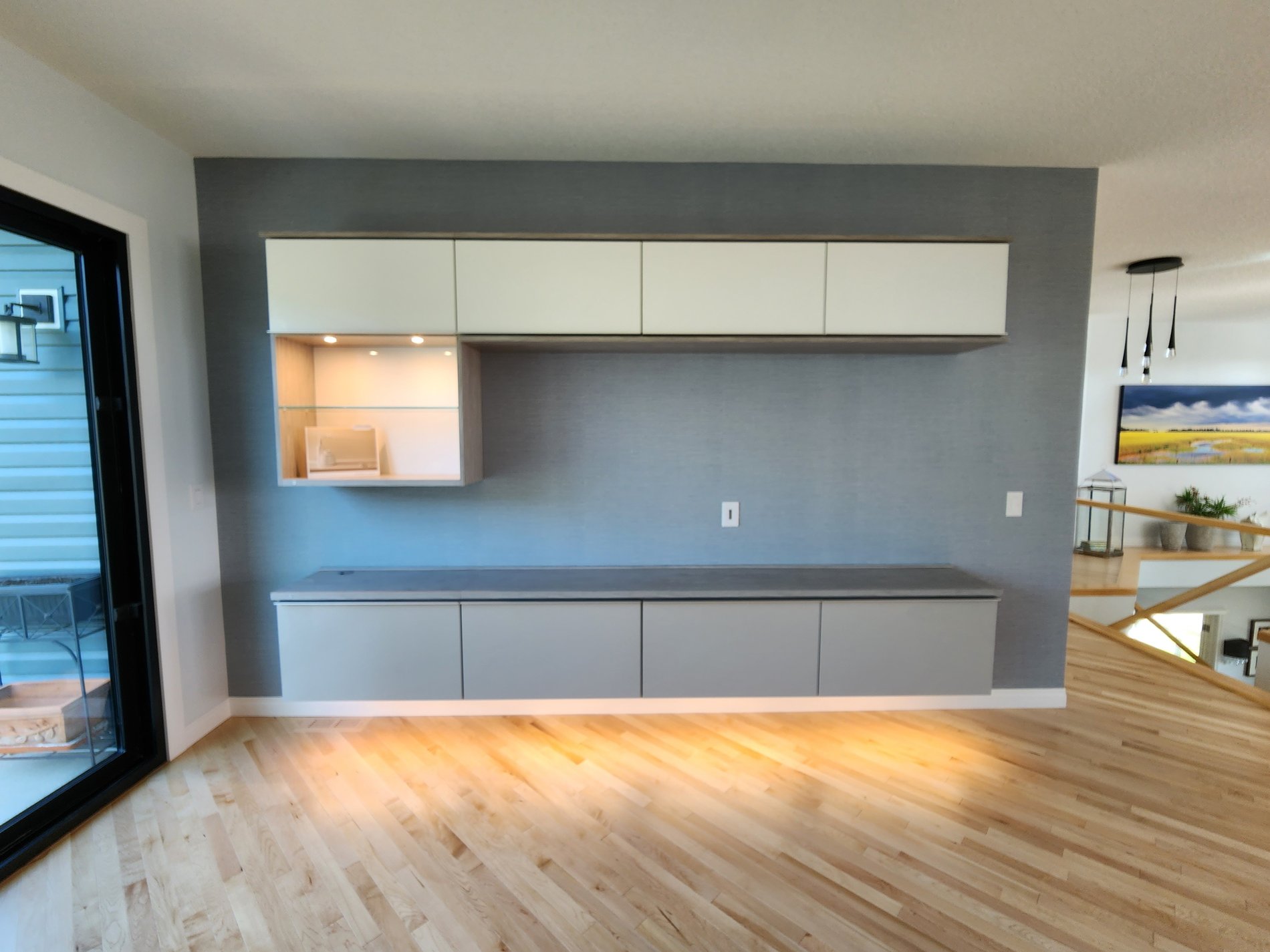 Modern media center with floating drawers, upper cabinets, and glass shelves. This media center has under mount lighting and pot lighting above the glass shelves. Designed in a gray and off white finish.