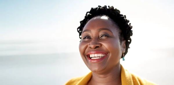 Woman in a yellow sweater excited for the new year and new hearing aids.
