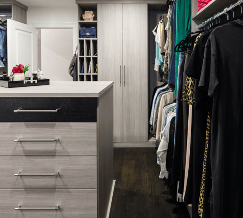 Img 5 California Closets Westchester County NY Gray Walk-in Closet Full Room Dressing Room with Double Hanging Dedicated Shoe Wall with Lighting and a Center Island with Black Leather Jewelry Drawers