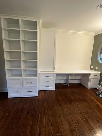White desk with floor-to-ceiling bookcases.