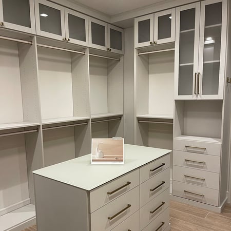 Custom linen-finish bedroom closet with gold hardware, linen pole inserts, shaker doors with frosted glass, and matte glass countertop.