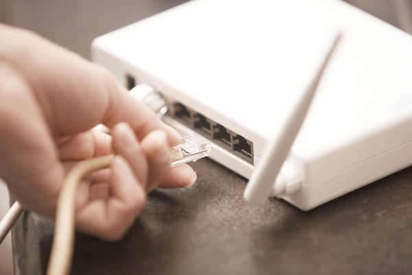 Hands plugging cable into router box