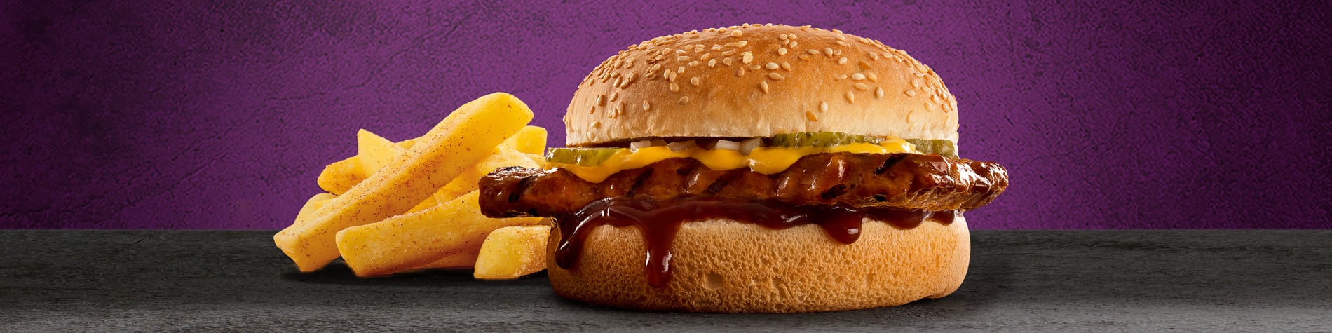 Flame-grilled Steers burger next to a full portion of chips against a purple background.