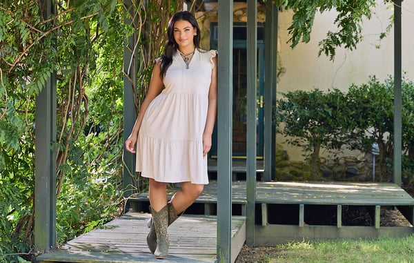Woman is wearing a plus size short ivory colored dress