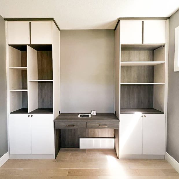 California Closets home office with floor to ceiling storage and a desk in the middle in a contrasting finish.