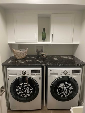 laundry room with washer and dryer, black stone countertop and white cabinets above