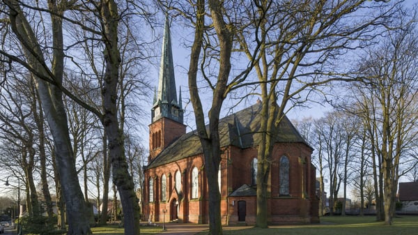Ein Kirchengebäude mit einem Kirchturm, von Bäumen umringt.