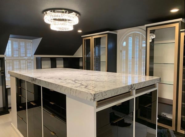 black and white closet island with gold glass doors