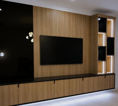 Custom modern media center and TV wall storage with warm oak wood finishes, matte black panels, floating cabinets, integrated LED lighting, built-in display shelving, and mounted TV storage by California Closets in Boca Raton, Florida. In South Palm Beach, Florida.