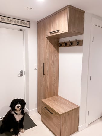 Mid wood toned mudroom with upper and side cabinetry with a small bench