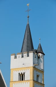 Nahaufnahme des Kirchturms vor blauem Himmel.