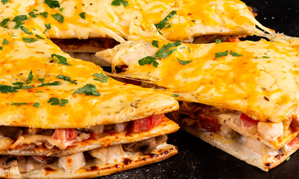 Chicken, meat and vegetarian pizzas on a wooden table.