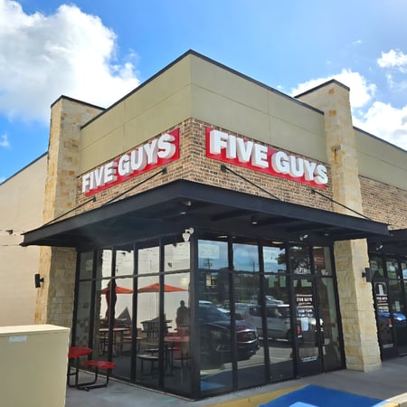 Exterior photograph of the Five Guys restaurant at 10463 TX-242 in Conroe, Texas.