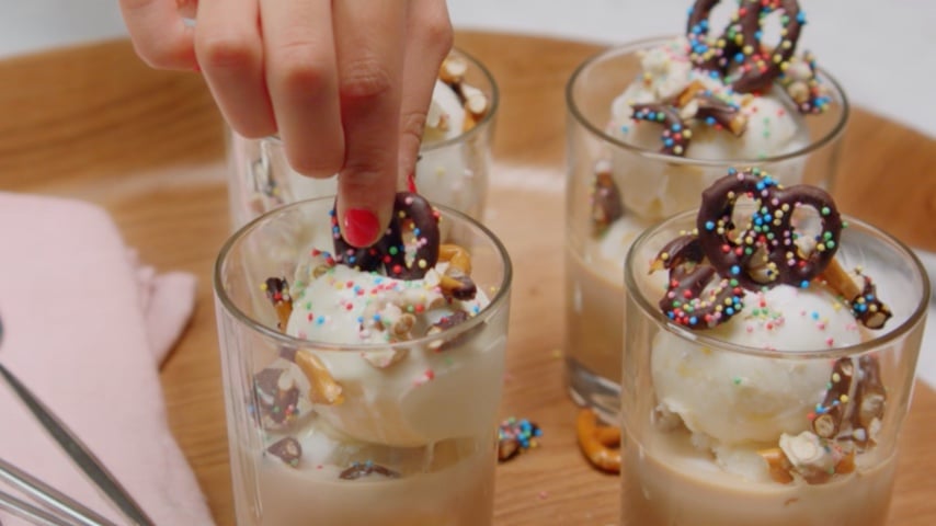 Decoration of Baileys-infused ice cream sundae with chocolate-covered pretzels