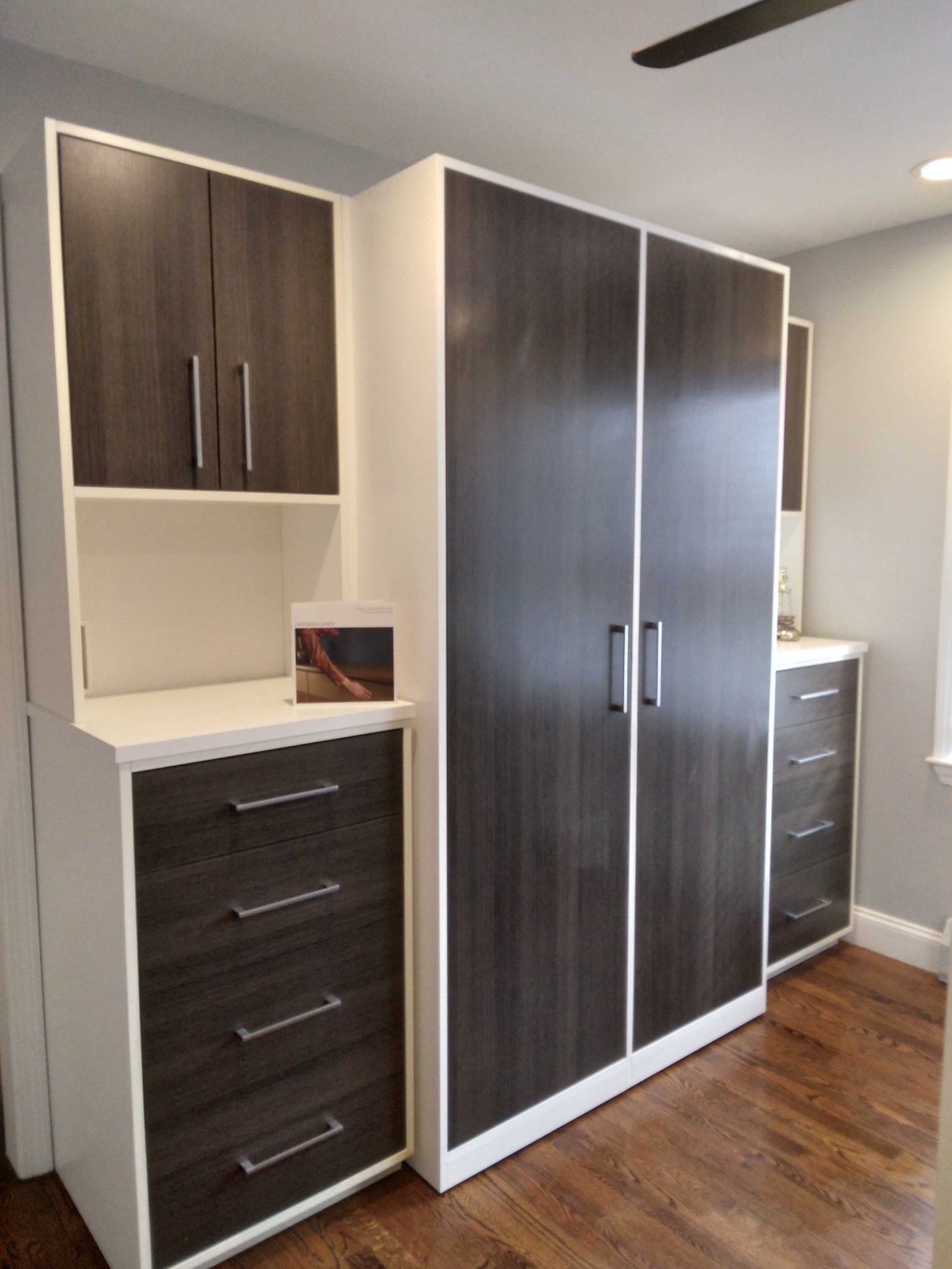 Wardrobe storage with dark wood doors and drawers and lighter wood bases.