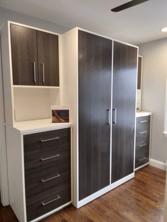 Wardrobe storage with dark wood doors and drawers and lighter wood bases.