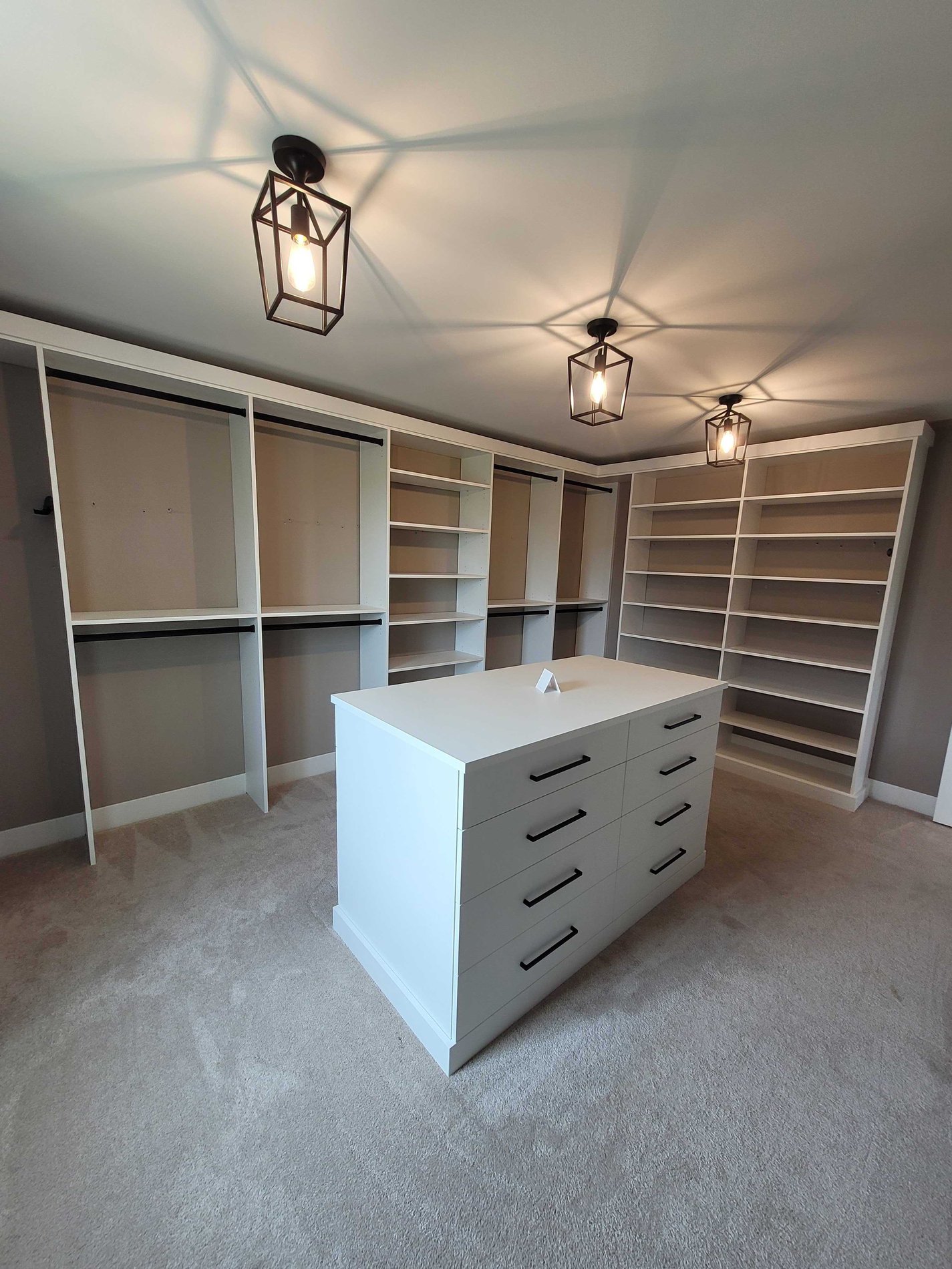 white walk-in closet with center island and black light fixtures