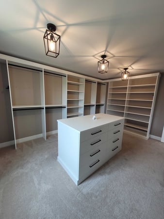 white walk-in closet with center island and black light fixtures