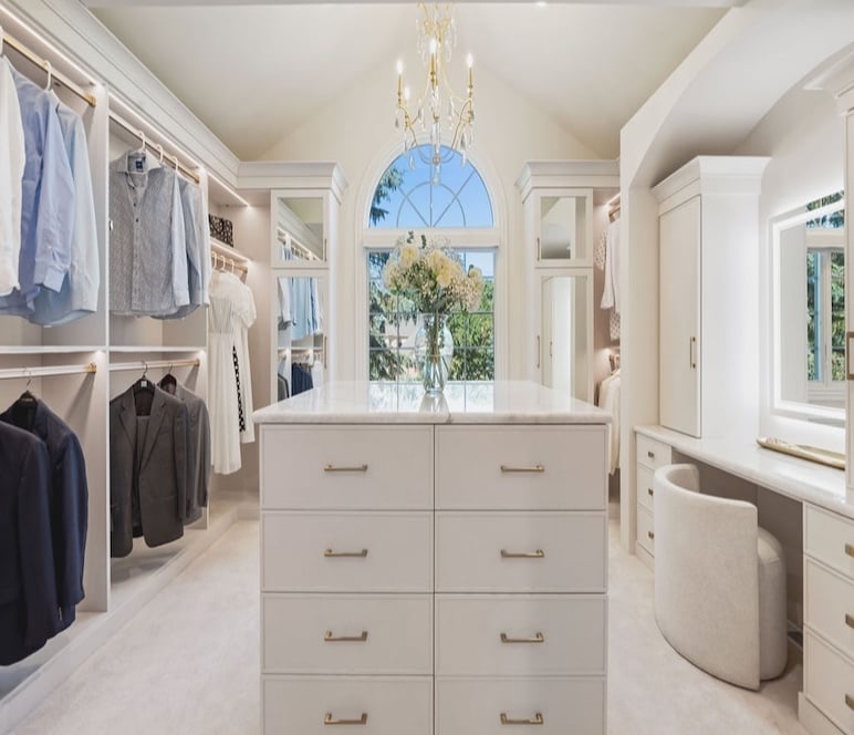 Custom Walk in closet with a light, island, and vanity