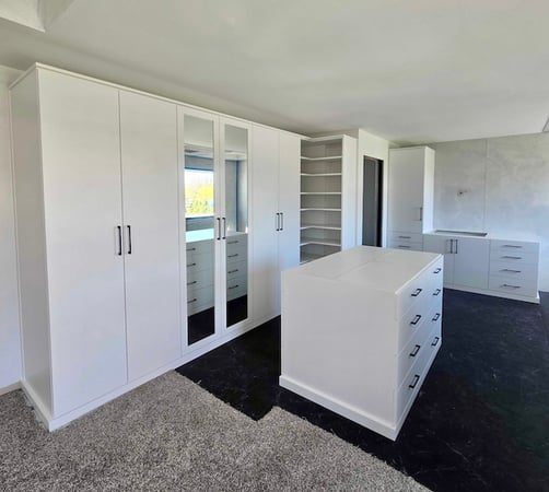 Bright white walk-in closet with custom shelving, built-in cabinets, center island, and drawer storage for elevated organization in Troy, Michigan