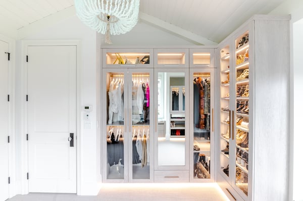 White, bright walk in closet with built in interior and toe kick lighting
