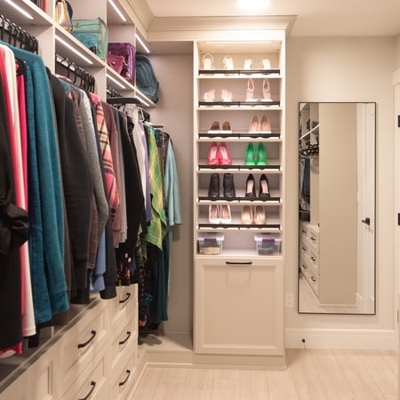 White walk in closet with upper hanging, lower drawers, floor to ceiling shoe organization, and lighting.