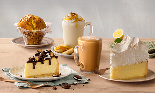 Famous Giant Muffin, Cinnamon Pancake hot drink, Salted Caramel hot drink, a slice of Lemon Meringue cake and a slice Oreo® Whispers Cheesecake.