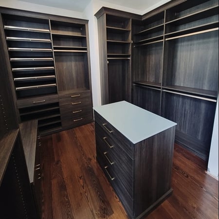 Dark brown walk-in closet organization with island California Closets New Orleans & Gulf Coast