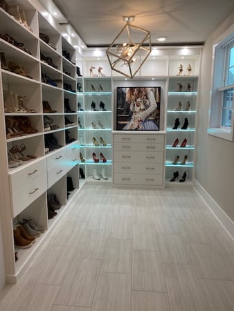 White primary closet with shoes, lighting, and drawers