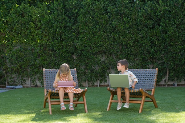 Young kids with laptops in backyard