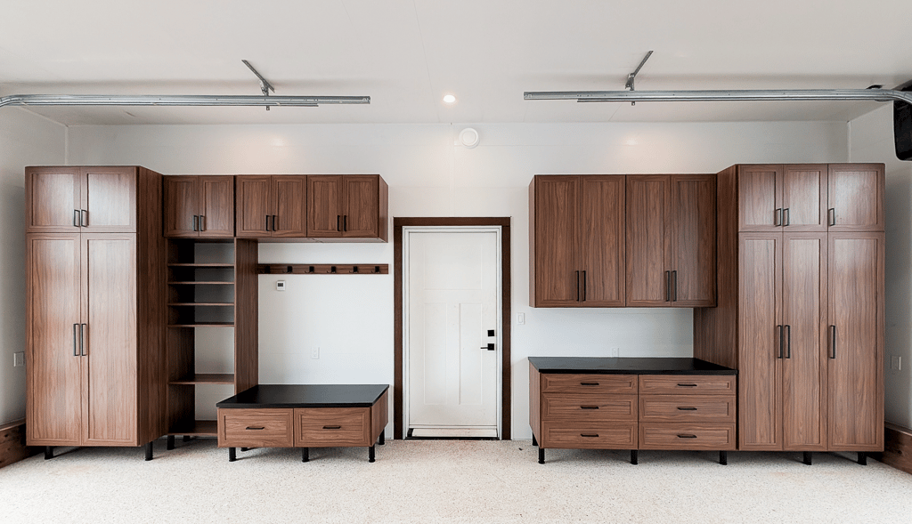 Upgraded garage storage designed in a mid-century finish with contrasting black countertop and bench top. Floor to ceiling storage, open shelving, and drawers provide enough storage for everyday essentials.