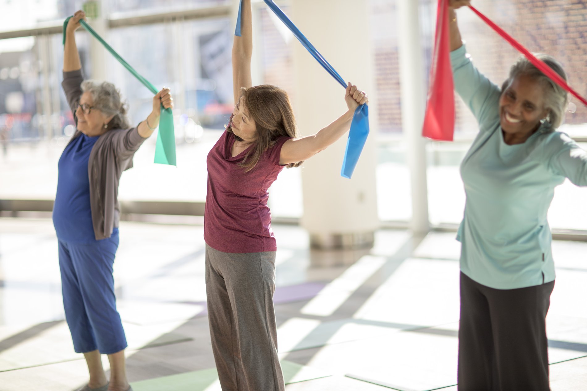 Tres mujeres mayores elongando en una clase de gimnasia