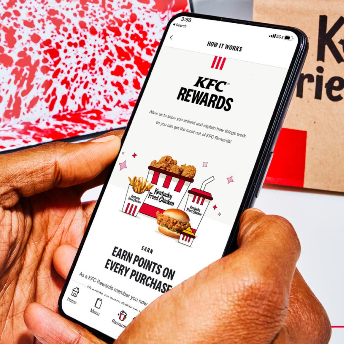 Person holding a smartphone with the details for the KFC® Rewards program on screen.