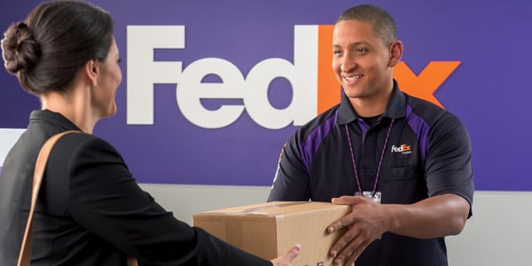 FedEx customer passing a box to FedEx employee