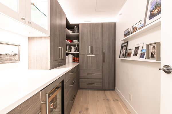 Wood tone pantry with white acrylic countertops and floating shelves