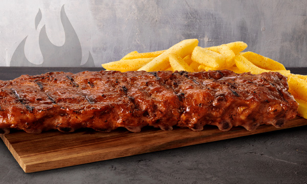 Single Loin pork rib rack with chips on a wooden board placed on a grey surface with a purple background.