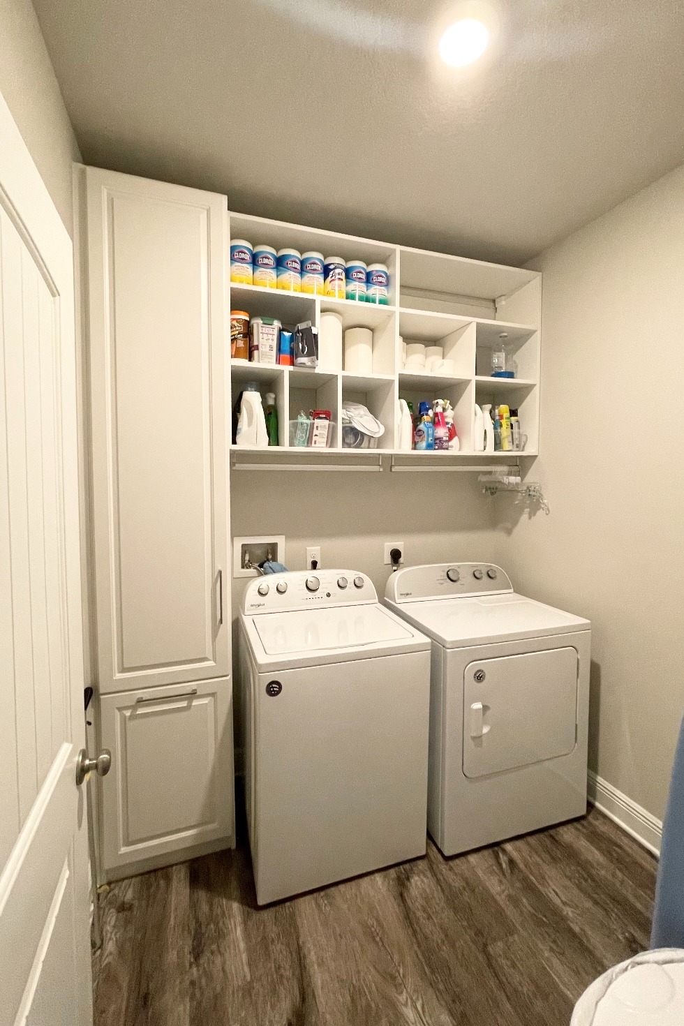 White cabinets in laundry room with hidden laundry hamper basket California Closets Pensacola & Panama City, Florida