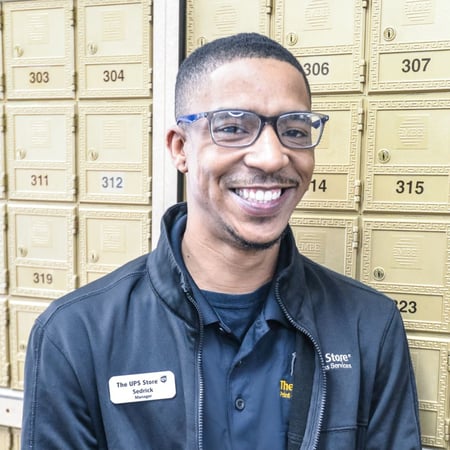 Smiling male associate standing in front of mailboxes in The UPS Store