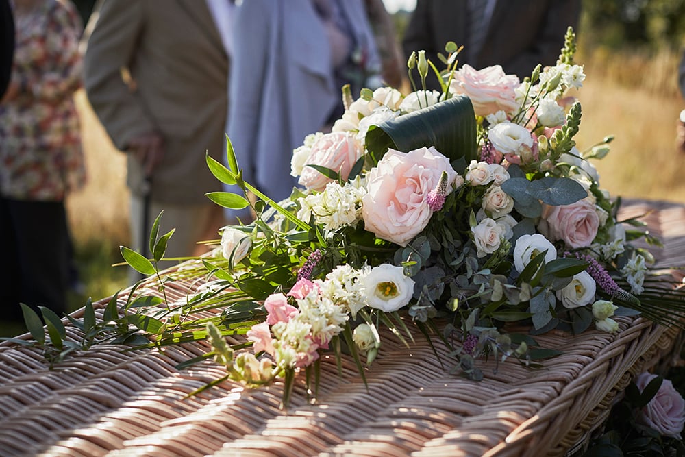 A pink spray rests on a bamboo coffin to represent an attended funeral