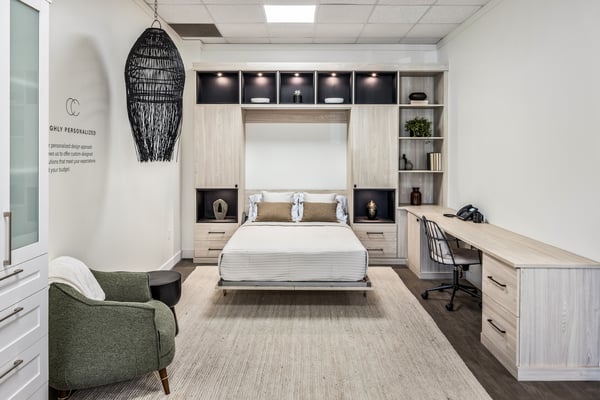 Wall bed with open shelving, cabinets and adjacent desk in light wood finish accented by dark inset boxes.
