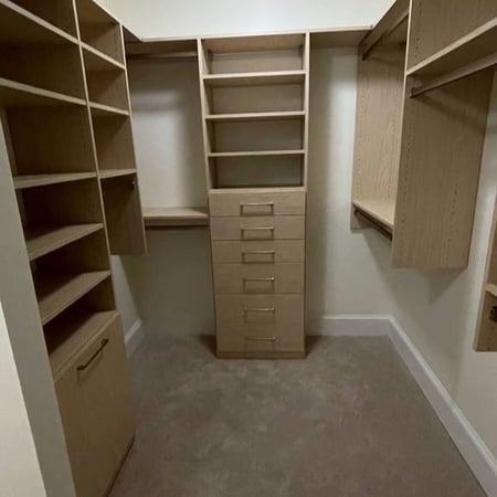 Richmond - Custom closets - walk-in closet with wood-tone shelving, drawers, and double hanging sections arranged symmetrically.